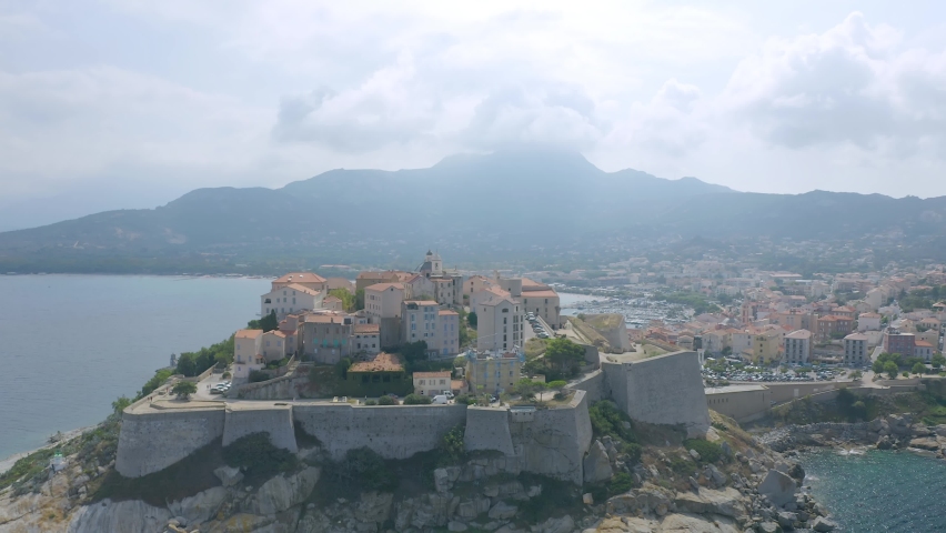 Aerial: Flight over historical citadel of Calvi, beautiful city on Corsica island, France, Europe Royalty-Free Stock Footage #1069878607