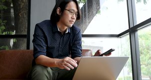 4K Video Slow motion asian man using mobile phone with computer notebook. Concept for people with mobile technology.