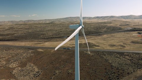 Drone Flying by Spinning Wind Turbine Propellers with Cars Driving in Background. Interstate 90 windmills in Eastern Washington aerial view