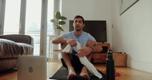 Mixed race male working out in living room holding sweat towel