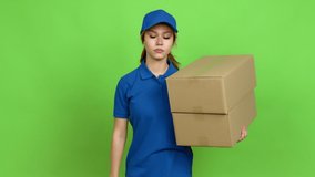 Young blonde teenager girl holding boxes for delivery doing bad signal over isolated background. Green screen chroma key