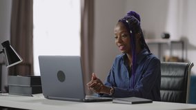young black woman is communicating by video chat on laptop, chatting with client or colleague from her home office, distant communication and remote job
