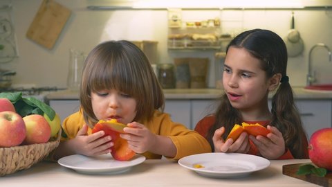 Happy Kids with mango fruit in hands. Cute boy and girl crazy eating mangoes healthy dietary nutritious at home in the kitchen. Healthy lifestyle, raw food
