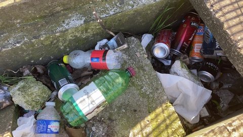 Paris Suburb, France - 31 March 2021 - Improper Waste Management - Used plastic water bottles, empty alcohol and beer bottles, soft drink cans lying on the side of the street.