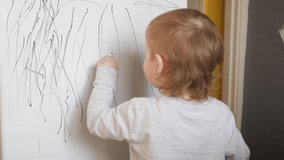 The child draws on the refrigerator, white canvas with a black felt-tip pen. View from the back. Little boy learns to paint, creativity. Horizontal. - Powered by Shutterstock - Get 15% off with code: PIKWIZARD15
