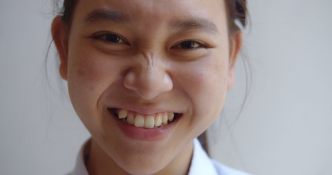 A young Asian teenage high school student girl is smiling happily.