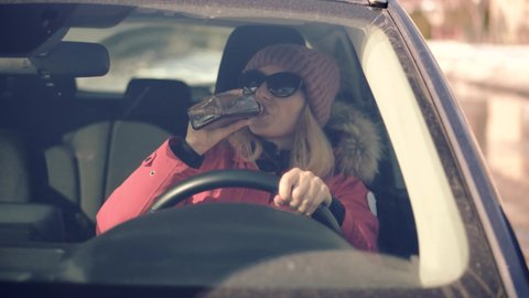 Drunken Driving Risk Car Accident. Woman Holding Alcohol Bottle In Car. Dangerous On Road Drunk Driving. Stress Unlawful Intoxicated Drive Auto. Female Drunk Driving On Car.Tired Illegal Vehicle Drive