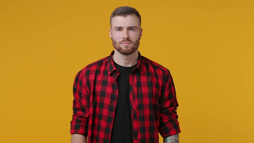 Displeased dissatisfied tattooed young man 20s in red shirt isolated on yellow background studio. People lifestyle concept. Tattoo translate life as a fight. Holding crossed hands in stop gesture say no. Royalty-Free Stock Footage #1069914652