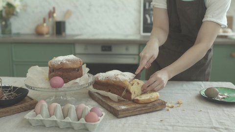 The girl's hands are cutting the Easter street. The girl cuts festive Easter bread into pieces. The girl decorates Easter bread.