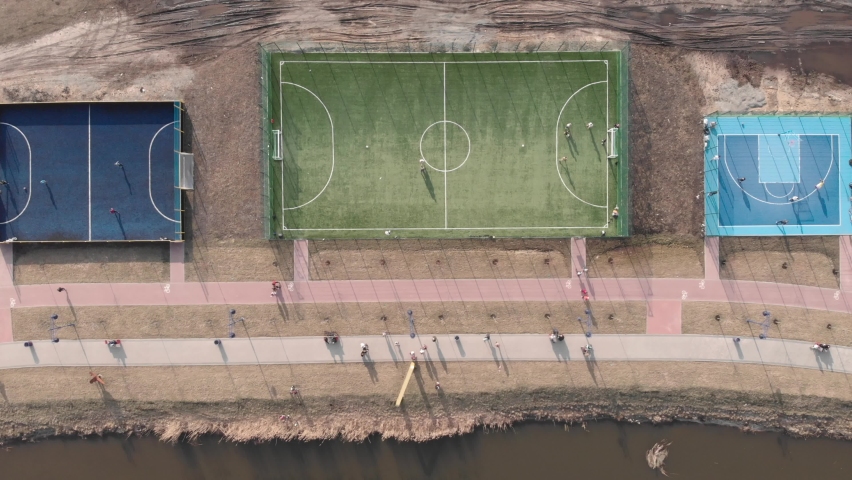 Modern sport area with training, football and basketball fields. Sportsmen playing games outdoor. Active sport zone along promenade in city district