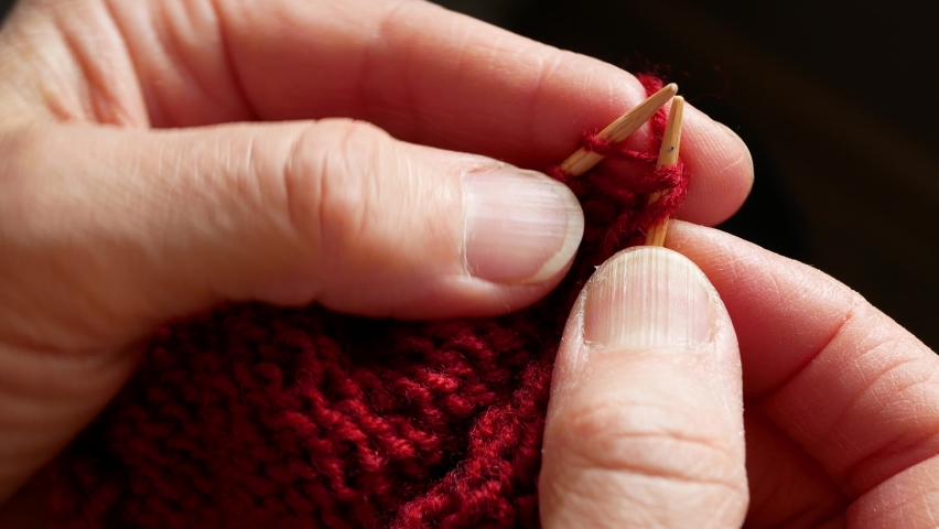 Knitting using wooden needles and burgundy yarn, close up. Hobby and leisure activity during lockdown | Shutterstock HD Video #1069924885