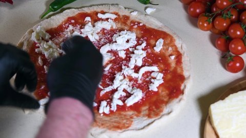Making Italian pizza Margherita: video of a pizza maker showing how to put buffalo mozzarella on the dough of a real Neapolitan high-dough Margherita pizza