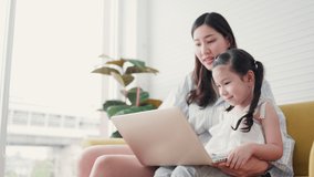 Single mother family teach her daughter laptop happy in living room home. Home study. Mom help children learn distance by video calling with Wi-Fi. Thinking skill in children. Concept Home school