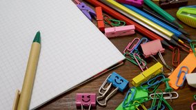 Colorful stationery on brown wooden background. Back to school concept. Ballpoint pen, paper notebook, eraser or rubber, colored pencils, sharpener, paper clips