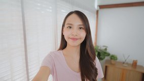 Point of view vlog or selfie camera of Asian beautiful happy woman blogger holding phone looking at camera, greeting and talking to friends or family on video call online. Technology lifestyle concept