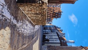 Vertical format video. Walking walk through the streets of the old old town of Riga in the spring. Bright sun with long shadows on the paving stones. Medieval buildings and churches. Latvia