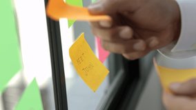 Business male hand pick the Colorful of post it at the wall. sticky note or paper note on the windows for note what to do in the office.