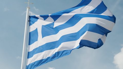 Slow motion of Greek flag rippling on the wind against blue sky.