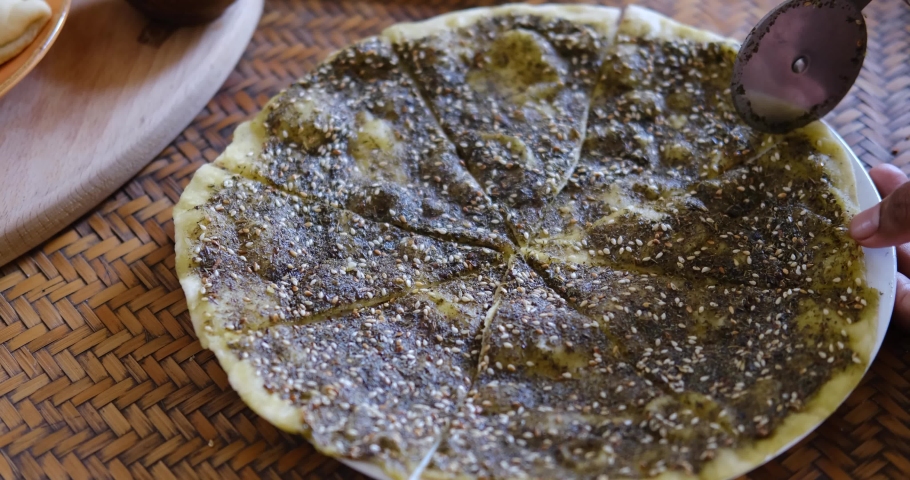 Close up of a hand cutting Zaatar Manakish - Flatbread topped with zaatar and olive oil. Traditional Arab food. Royalty-Free Stock Footage #1069962706