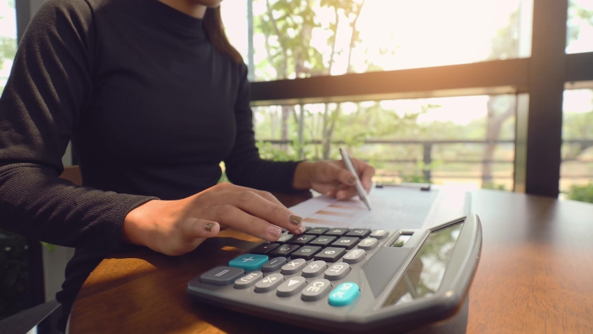 Woman accountant working on desk using calculator for calculate and checking finance report. 4K | Shutterstock HD Video #1069964092
