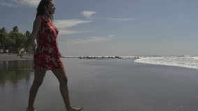 Woman walking in waves on sunny ocean beach , San Blas, La Libertad, El Salvador