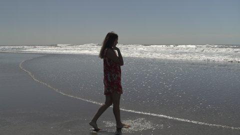Tracking shot of woman walking in waves on ocean beach , San Blas, La Libertad, El Salvador