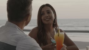 Smiling couple talking and toasting with cocktails near ocean , El Tunco, La Libertad, El Salvador