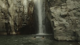 Tilt up from playful swimming couple splashing each other to waterfall on cliff , Tamanique, La Libertad, El Salvador - Powered by Shutterstock - Get 15% off with code: PIKWIZARD15