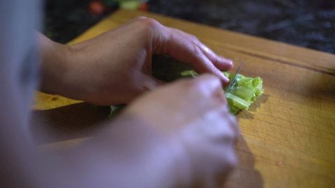 Close up view of unrecognizable female cook with grey apron making salad at home -