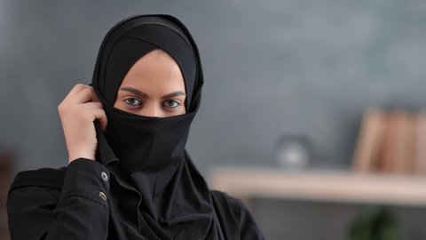 Portrait beautiful Arabic woman hidden face under niqab posing at traditional Muslim headscarf outfit. Facial pretty mixed race lady with natural beauty wearing black hijab. Shot with RED camera in 4K