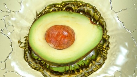 Super Slow Motion Shot of Fresh Avocado Falling and Splashing into Oil at 1000 fps.