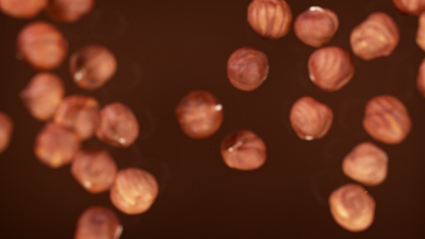 Super Slow Motion Shot of Hazelnuts Falling into Melted Chocolate at 1000 fps. Royalty-Free Stock Footage #1069983409