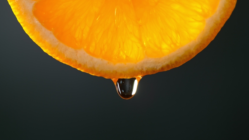Super Slow Motion Macro Shot of Water Drop Falling from Fresh Orange Slice on Black at 1000fps. Royalty-Free Stock Footage #1069983424