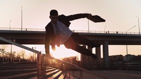 Businessman in jacket and tie with a suitcase in his hands jumps over an obstacle on background city in the sunset light. Office worker makes a trick through parapet. Concept overcoming difficulties. - Powered by Shutterstock - Get 15% off with code: PIKWIZARD15