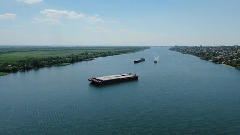 Top down view of a cargo ship in a canal of green color. Footage. Vessel floating down the river. Cargo ships in the canal. Transportation of goods by water