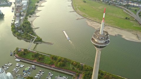 Rhine Tower (Rheinturm) In Dusseldorf Germany Overlooking Pedestrian Bridge And Buildings At Rhine River - aerial drone