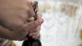Caucasian hand opening a bottle of red wine with bottle opener with real cork and the catering in the background - Powered by Shutterstock - Get 15% off with code: PIKWIZARD15