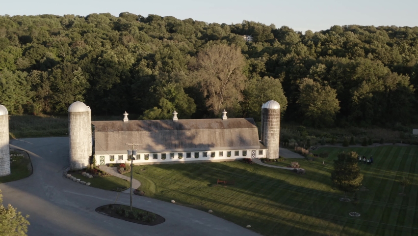 Old farmhouse and silos in aerial orbiting view