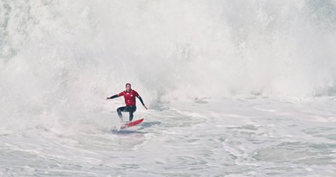 NAZARE, PORTUGAL - 07 FEBRURARY, 2021: Male surfer riding huge wave at Nazare beach, Portugal, Europe. Sportsman falling from the surfboard in atlantic ocean. 4k footage in slow motion