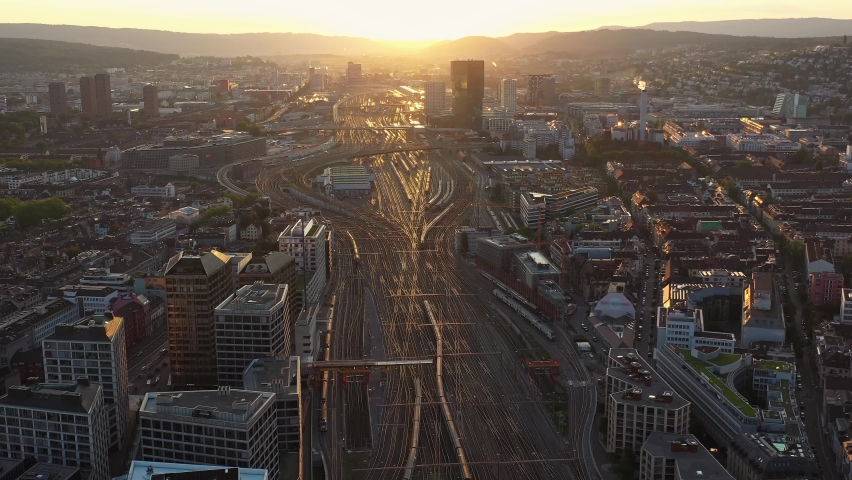 Aerial drone footage of the sunset over the Zurich train station and railroad tracks in the middle of the city downtown district in Switzerland