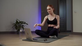 Girl doing body bends while sitting on the exercise mat. Long shot