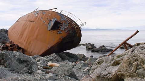 Rusty shipwreck abandoned on the rocky beach. Closeup with ship bow