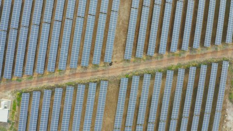 Aerial view of solar panels or solar cells on the roof in farm. Power plant with lake or river, renewable energy source in Thailand. Eco technology for electric power in industry. Photovoltaic cells