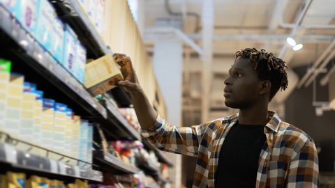 African american guy chooses products in the grocery store, put it to the cart