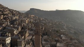 Drone video of the minaret of the mosque in the old town at sunrise. A beautiful city with Middle Eastern architecture in Misopotamia. Aerial view Mardin Turkey.