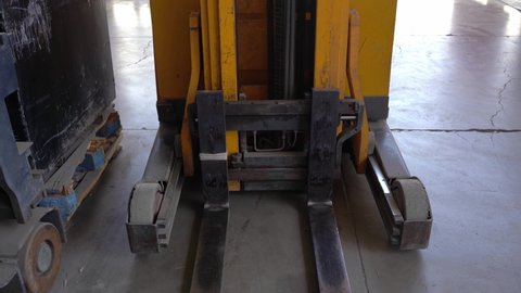 Forks of yellow forklift at factory. Heavyweight transportation machine, industrial use concepts