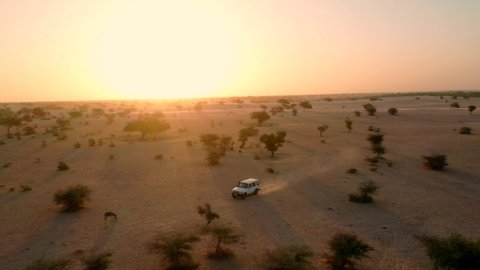 Drone tracking of a car driving in the Sahara desert of Chad, Africa, at sunrise