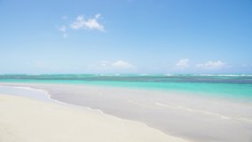 Clean and wide sea beach with white sand and transparent waves of the Indian Ocean 4k stock video footage. Beach and sea summer sunny landscape. Paradise nature background, no people, copy space.