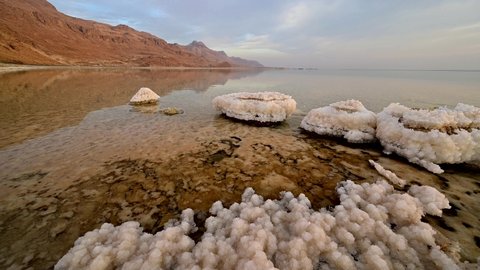 Beautiful Israeli landscape of the Dead Sea, the lowest place on Earth: salt formations and clouds with Judean Desert mountain in the background