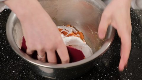 The pastry chef mixes the dough for the macarons in a stainless steel bowl.